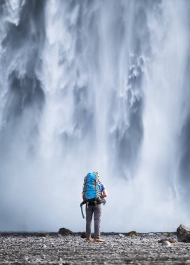 Skogafoss şelalesinde sırt çantalı bir turist. İzlanda 'da seyahat ediyorum. İzlanda 'daki aile mekanında bir turist. Seyahat - resim