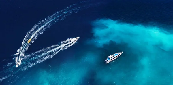 Fast boats on the sea in Bali, Indonesia. Aerial view on speed boats on blue water at sunny day. Seascape from air. Top view from drone. Travel - image