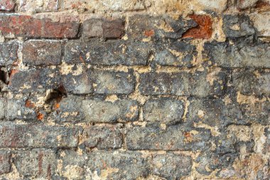 Kirli kırmızı tuğlalardan oluşan eski bir duvar.