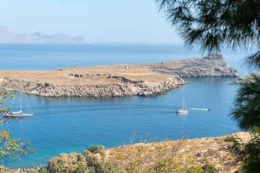View of an island and several boats. Beautiful azure water and sunny summer day. 