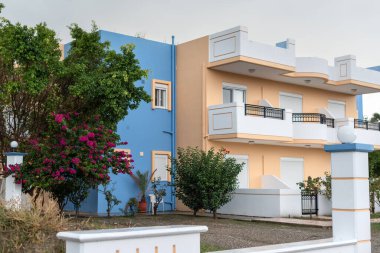 Akdeniz 'de çiçekli begonvilli güzel bir ev. Köyde beyaz kapıları, pencereleri ve balkonları olan mavi ve sarı bir ev. 