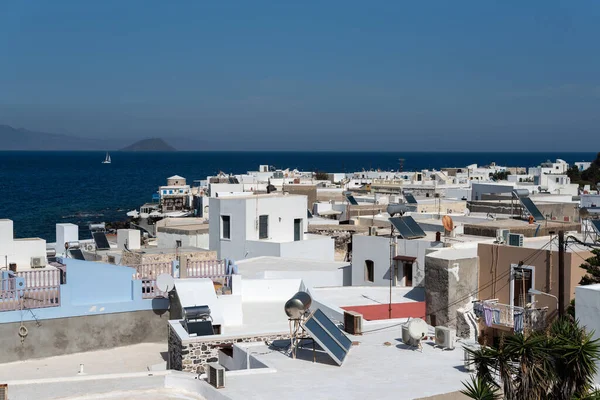 Yunanistan 'da geleneksel Akdeniz kenti Mandrakion görüşü. Denizin önündeki beyaz evler ve fotoğrafta yalnız beyaz tekne.. 
