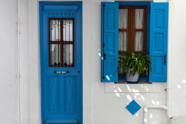 Yunanistan 'da bir evin geleneksel dış cephesi Nisyros. Mavi pencereli ve kapılı beyaz ev.