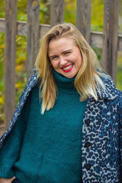 Tahta bir çitin arkasında poz veren güzel sarışın kız.