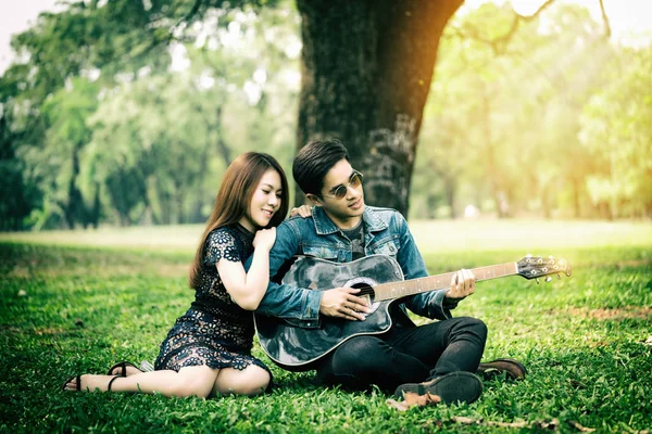 Couple playing guitar in the park