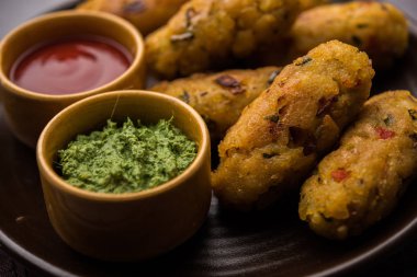 Vejetaryen Poha Pirzolası ya da yassı pirinç köftesi domates ketçap ve yeşil baharatla servis edilir.