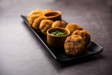 Vejetaryen Poha Pirzolası ya da yassı pirinç köftesi domates ketçap ve yeşil baharatla servis edilir.