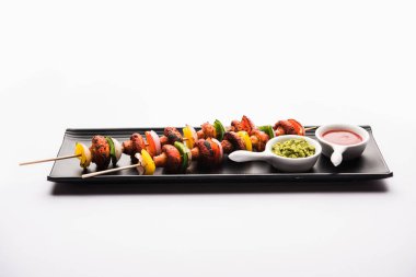 Barbekü ya da tandır mantarlı Tikka, yeşil turşu ve ketçaplı bir tabakta servis edilir. seçici odak