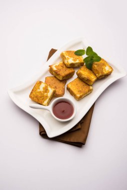 Amritsari Paneer Tikka besan, chat masala ve baharatlardan yapılmış süzme peynir küpleriyle tavada kızartılmış ve ketçapla servis edilmiş.