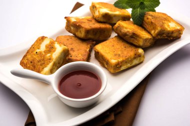 Amritsari Paneer Tikka besan, chat masala ve baharatlardan yapılmış süzme peynir küpleriyle tavada kızartılmış ve ketçapla servis edilmiş.