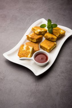 Amritsari Paneer Tikka besan, chat masala ve baharatlardan yapılmış süzme peynir küpleriyle tavada kızartılmış ve ketçapla servis edilmiş.