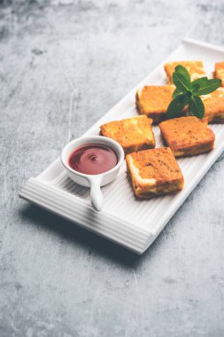 Amritsari Paneer Tikka besan, chat masala ve baharatlardan yapılmış süzme peynir küpleriyle tavada kızartılmış ve ketçapla servis edilmiş.