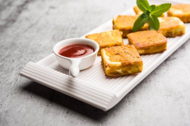 Amritsari Paneer Tikka besan, chat masala ve baharatlardan yapılmış süzme peynir küpleriyle tavada kızartılmış ve ketçapla servis edilmiş.