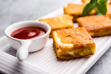 Amritsari Paneer Tikka besan, chat masala ve baharatlardan yapılmış süzme peynir küpleriyle tavada kızartılmış ve ketçapla servis edilmiş.