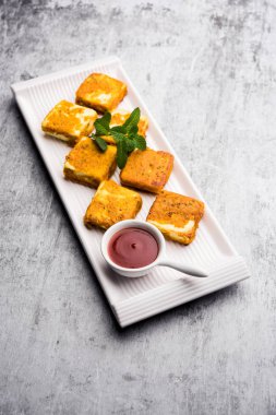 Amritsari Paneer Tikka besan, chat masala ve baharatlardan yapılmış süzme peynir küpleriyle tavada kızartılmış ve ketçapla servis edilmiş.