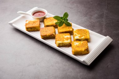 Amritsari Paneer Tikka besan, chat masala ve baharatlardan yapılmış süzme peynir küpleriyle tavada kızartılmış ve ketçapla servis edilmiş.