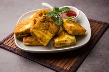 Amritsari Paneer Tikka besan, chat masala ve baharatlardan yapılmış süzme peynir küpleriyle tavada kızartılmış ve ketçapla servis edilmiş.