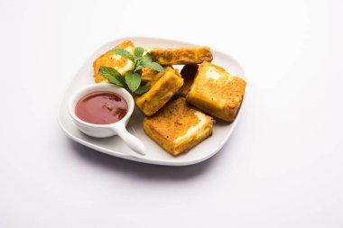 Amritsari Paneer Tikka besan, chat masala ve baharatlardan yapılmış süzme peynir küpleriyle tavada kızartılmış ve ketçapla servis edilmiş.