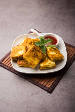 Amritsari Paneer Tikka besan, chat masala ve baharatlardan yapılmış süzme peynir küpleriyle tavada kızartılmış ve ketçapla servis edilmiş.