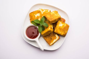 Amritsari Paneer Tikka besan, chat masala ve baharatlardan yapılmış süzme peynir küpleriyle tavada kızartılmış ve ketçapla servis edilmiş.