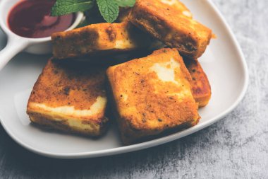 Amritsari Paneer Tikka besan, chat masala ve baharatlardan yapılmış süzme peynir küpleriyle tavada kızartılmış ve ketçapla servis edilmiş.