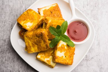 Amritsari Paneer Tikka besan, chat masala ve baharatlardan yapılmış süzme peynir küpleriyle tavada kızartılmış ve ketçapla servis edilmiş.