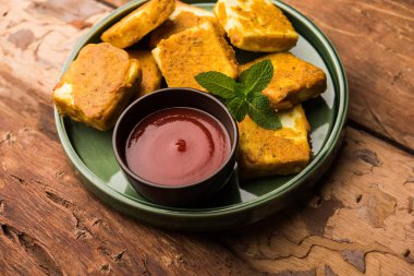 Amritsari Paneer Tikka besan, chat masala ve baharatlardan yapılmış süzme peynir küpleriyle tavada kızartılmış ve ketçapla servis edilmiş.