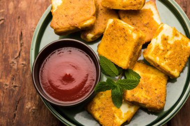 Amritsari Paneer Tikka besan, chat masala ve baharatlardan yapılmış süzme peynir küpleriyle tavada kızartılmış ve ketçapla servis edilmiş.