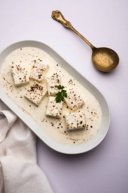 Paneer Dum Kali Mirch / Kalimirch, üzerine beyaz kremalı sos ve karabiber tozu serpiştirilmiş. Bir kasede servis edilir. Seçici odak