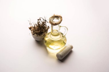 Ayurvedic Maha Bhringraj or Mahabhringraj Hair Oil with dried leaves and mortar, selective focus clipart