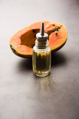 Papaya seed Oil with Raw Papita over moody background. selective focus clipart
