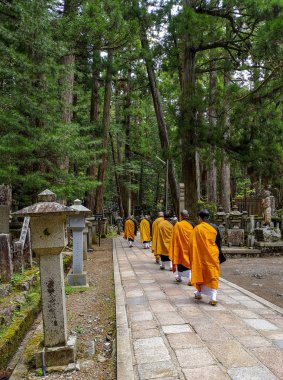 Monks walking on the 2 km long path with ancient tombs in the Okunoin cemetery towards the mausoleum of Kobo Daishi in the Unesco site Koyasan, Japan clipart
