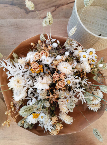 Dried flower arrangement for a wedding in neutral soft beige and white tones on a wooden background