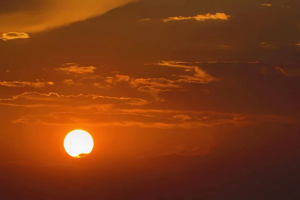 Sun in the sky with clouds at sunset.