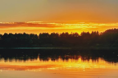 Gün batımı göl, suda ağaçların yansıması üzerinde.