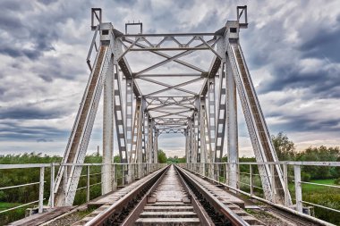 Metal demiryolu köprüsü fırtınalı bir gökyüzünün arka planına karşı.