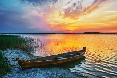 Gölde gün batımı, kıyıda balıkçı teknesi.
