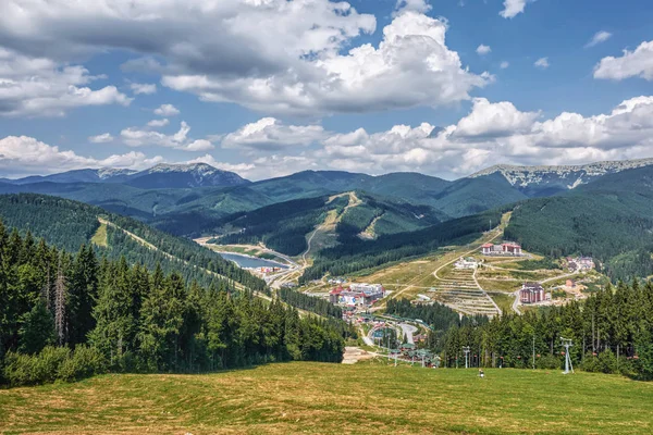 Dağlar, ormanlar, vadide ve gökyüzünde bulutlu küçük bir kasaba.