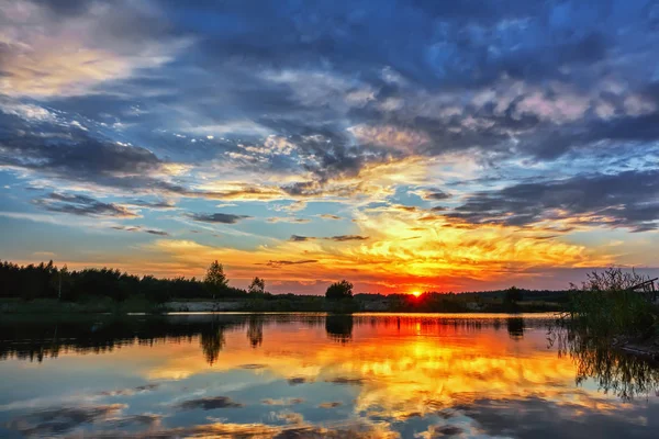 Gölde gün batımı - güneş kıyı şeridinin siluetinin üzerinde.