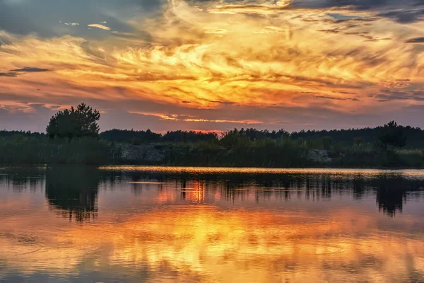 Sunset on the lake - sky with clouds over silhouette of coastline.