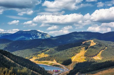 Mountains, forests and sky with clouds. Lake beach in valley.(Bukovel city, Ukraine).