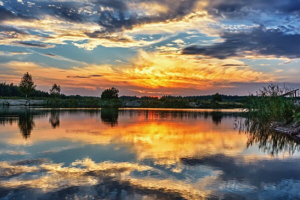 Sunset on the lake - sky with clouds over silhouette of coastline.