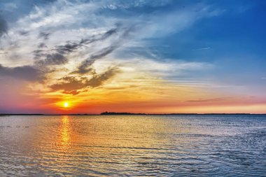 Gölün üzerinde gün batımı - bulutlu gökyüzü ve suya yansıyan güneş.