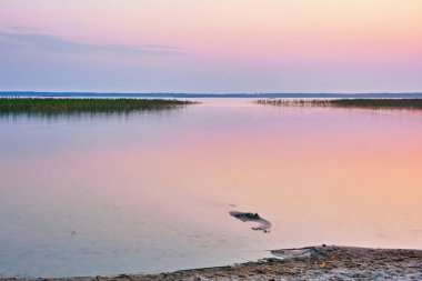 Gölün kumlu kıyısında gün doğumu.