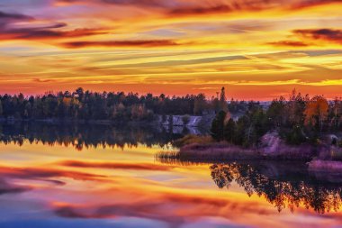 Ormanla kaplı bir gölün kayalık kıyısında alacakaranlık..