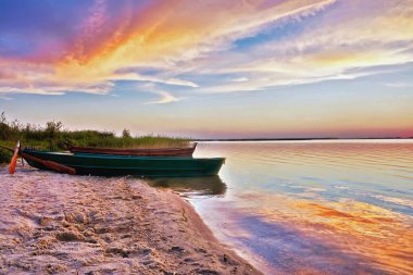 Gölde balıkçı tekneleri sahilde günbatımı.