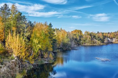 Sonbahar manzarası. Kayalık kıyıları ve ormanlarıyla gölün üzerinde güneşli bir gün..