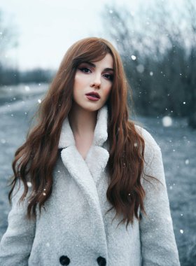 Dışarıda palto giyen genç bir kadın.