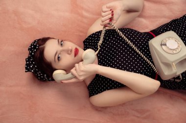Genç ve güzel bir kadın telefonuyla yatıyor.
