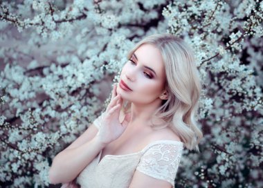 Çiçek açan ağaç arka planında poz veren genç bir kadının portresi